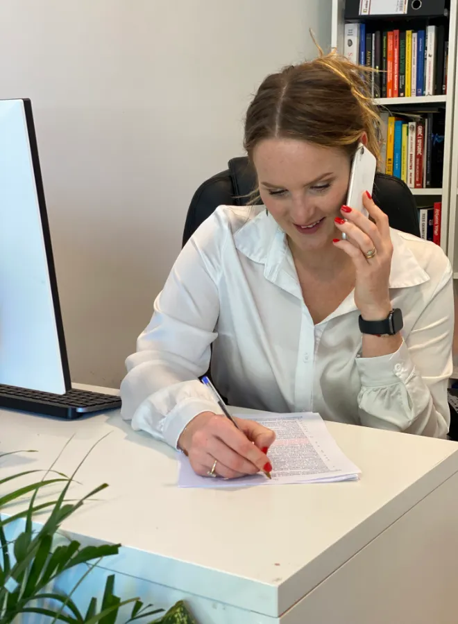 Marta Holewa, a nutritionist, talking on the phone while sitting at a desk in her office and making a note on a piece of paper.