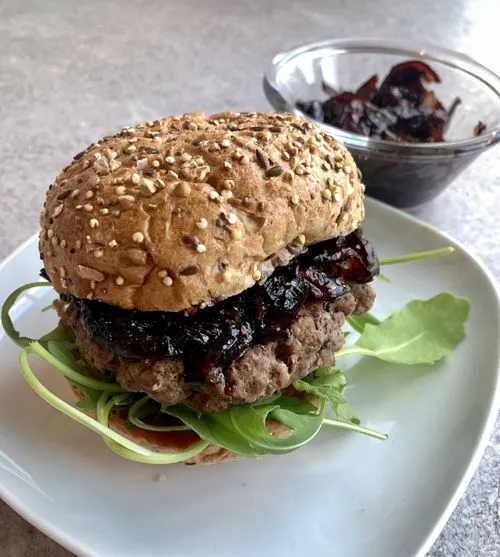 A burger on a plate next to a bowl of sauce.
