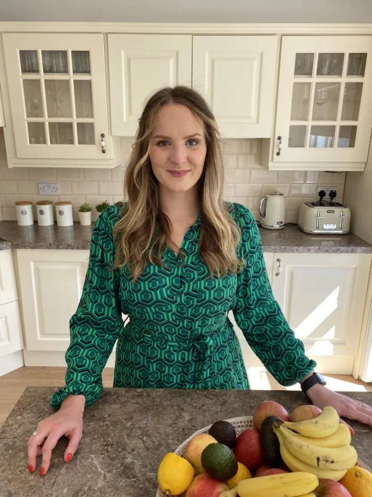 Nutritionist Marta Holewa posing next to a bowl of fruit in the kitchen